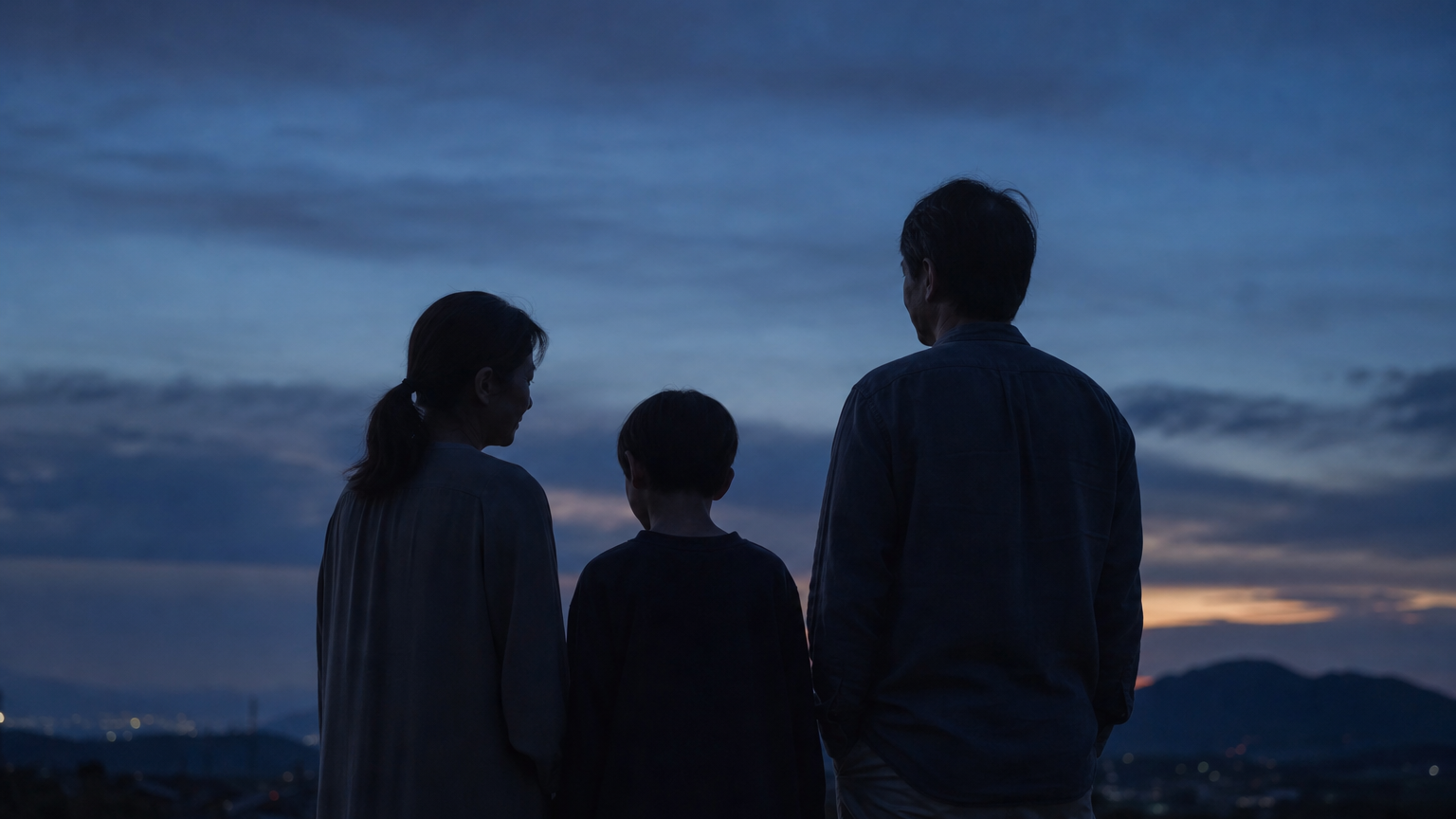 夕暮れの中、家族3人が並んで景色を眺める後ろ姿（家族との関係が変わった様子を象徴するカット）